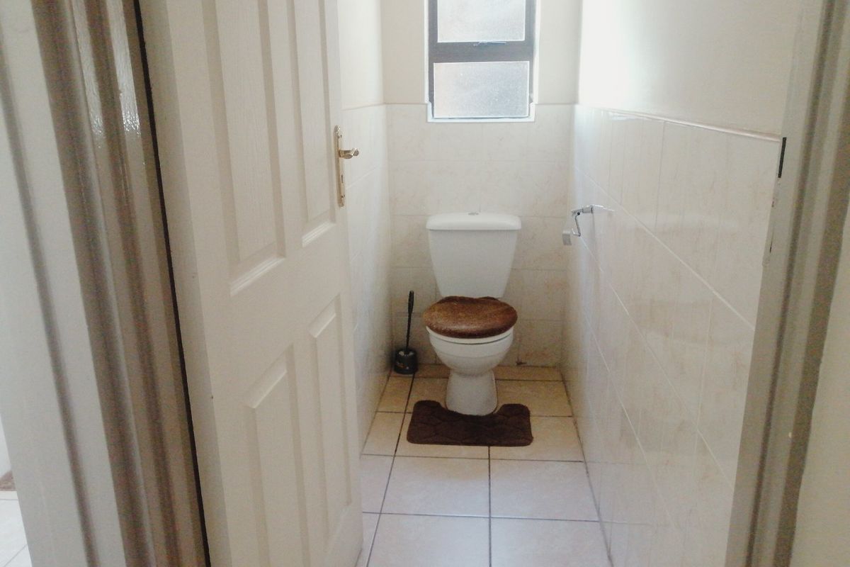 A compact, functional guest toilet featuring tiled walls and flooring, providing a clean and simple layout.