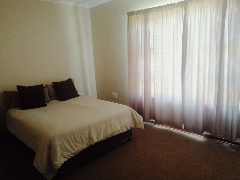 A standard bedroom featuring carpeted flooring and large window curtains, providing a neutral and functional living space.