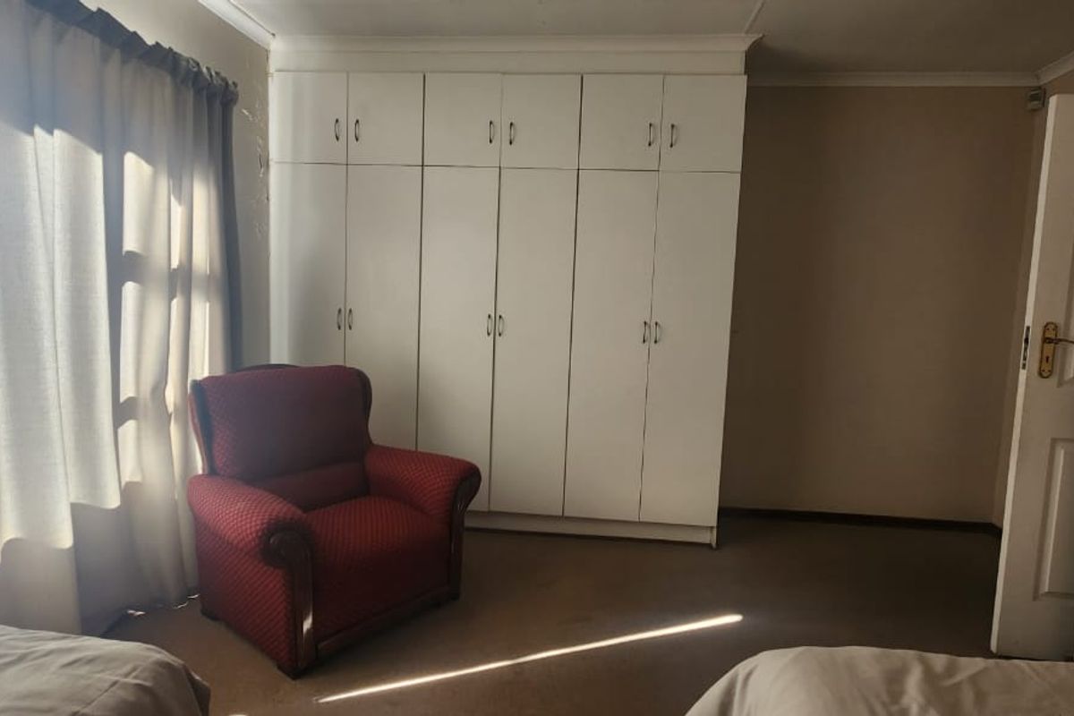A bedroom featuring white built-in cupboards, neutral wall finishes, and carpeted flooring.