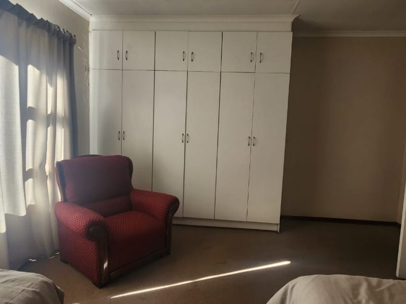 A bedroom featuring white built-in cupboards, neutral wall finishes, and carpeted flooring.