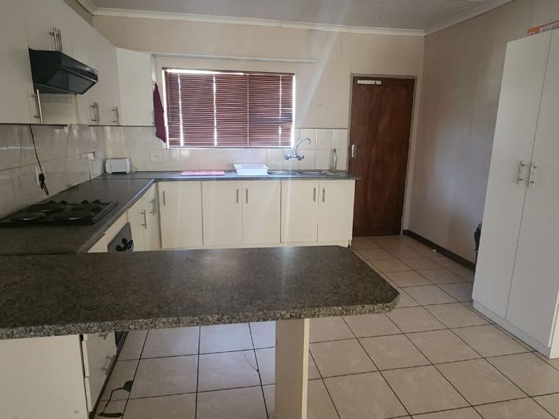 Functional kitchen featuring built-in cabinetry, laminate countertops, gas hob, extractor fan, and tiled flooring with a neutral backsplash.