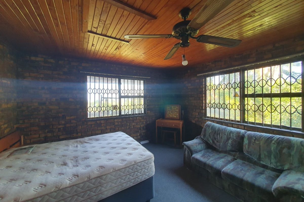 Bedroom featuring exposed brick walls, a timber tongue and groove ceiling, and security bars on the windows.