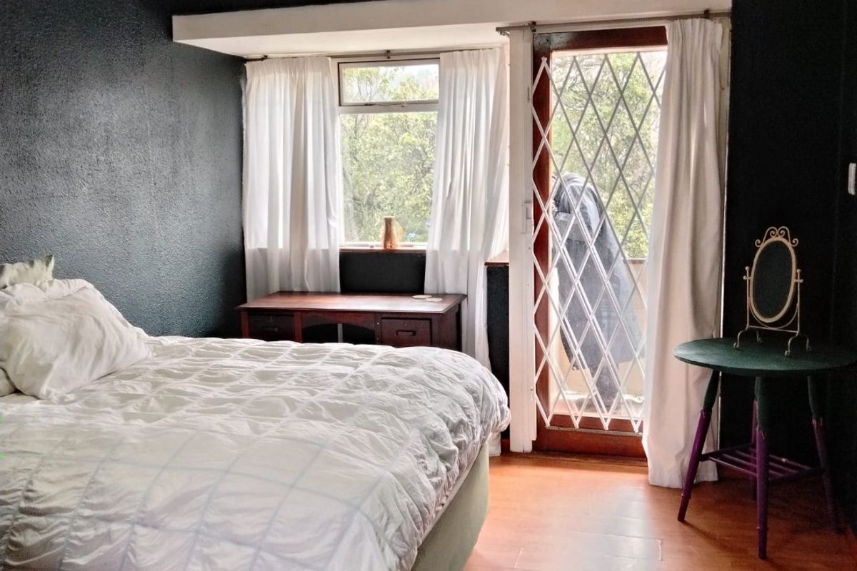 A bedroom featuring dark painted walls, laminate flooring, and a security gate leading to an outdoor area.