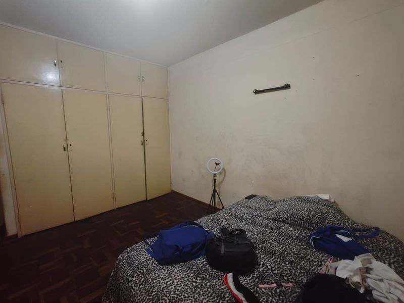 Bedroom featuring parquet flooring and extensive built-in cupboard storage, requiring cosmetic updates to the wall finishes.
