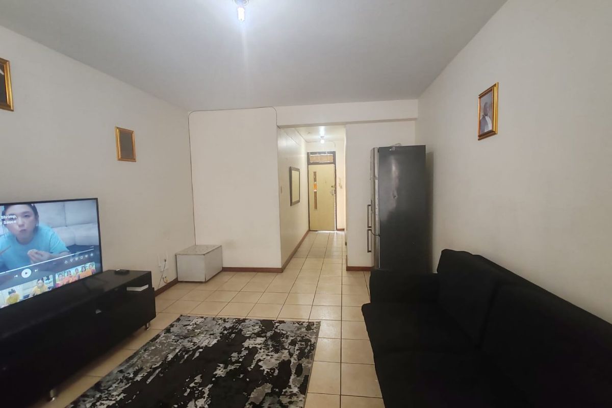 A living room area featuring tiled flooring and a direct view towards the apartment entrance.