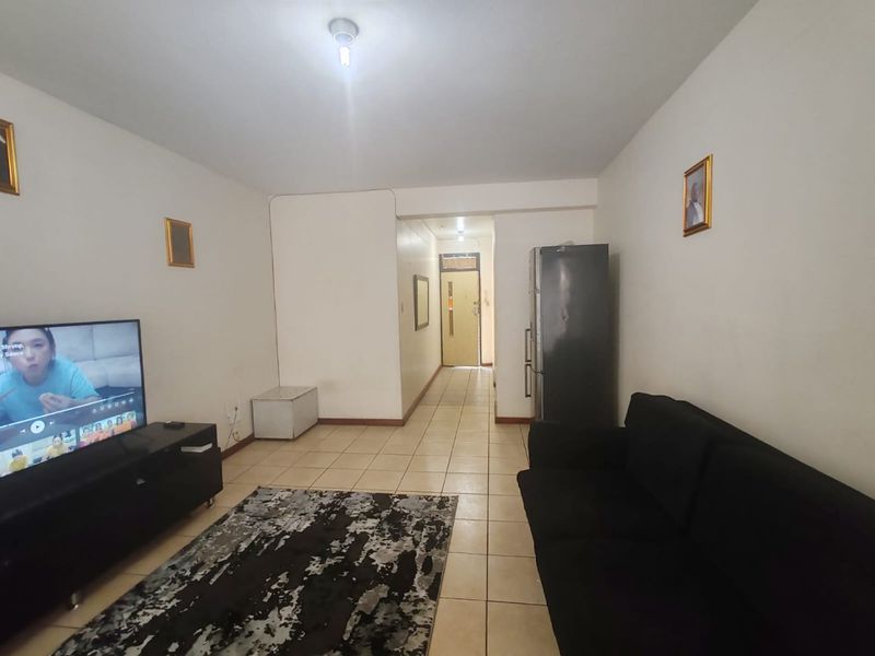 A living room area featuring tiled flooring and a direct view towards the apartment entrance.