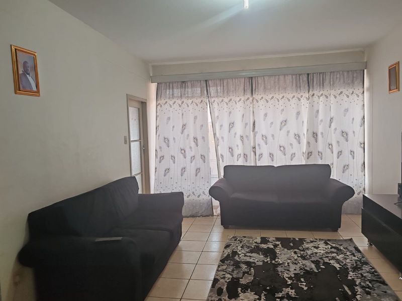 A living room featuring tiled flooring and a large sliding door with curtains, providing access to the exterior.