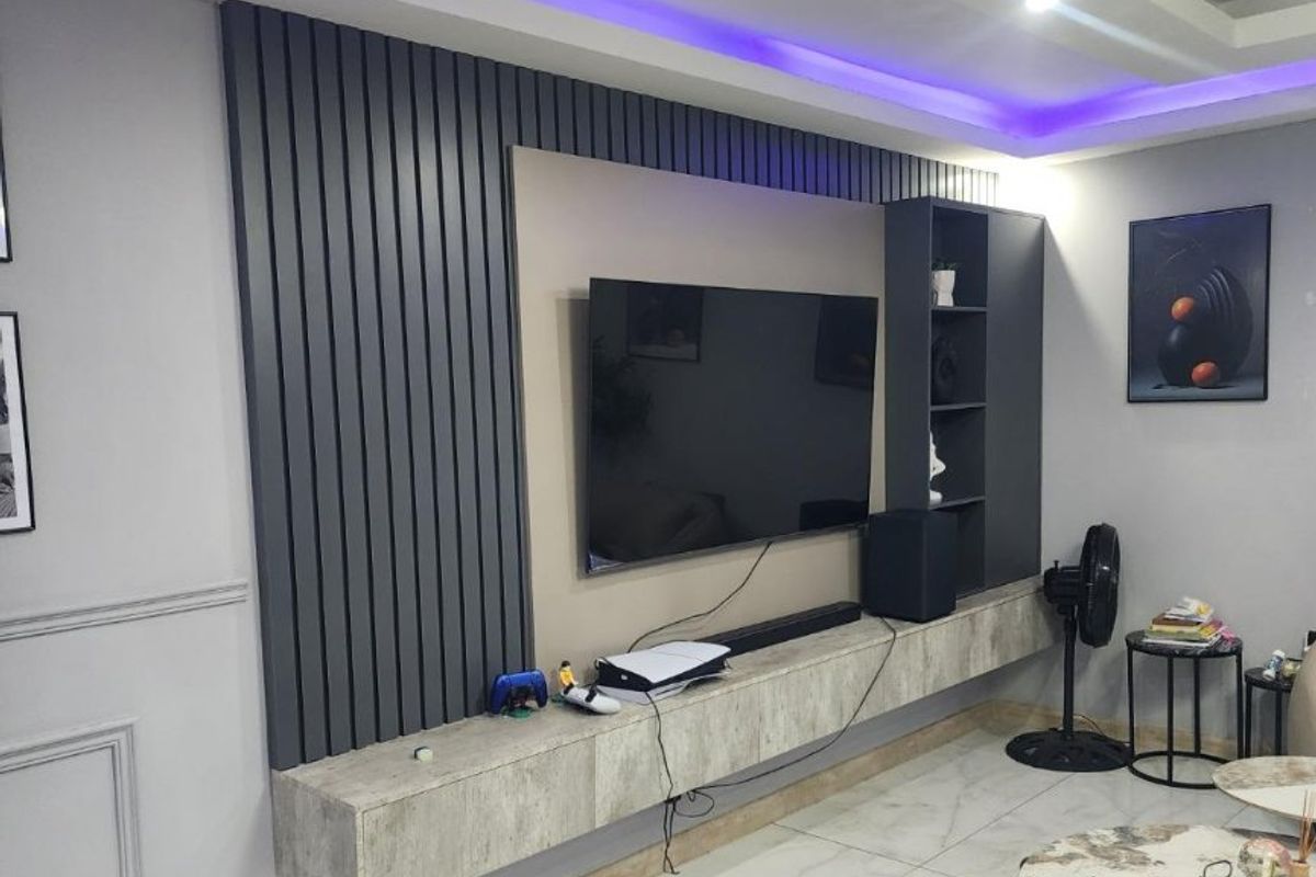 Modern living room featuring a custom built-in media wall with slatted paneling, integrated shelving, and ambient LED ceiling lighting.