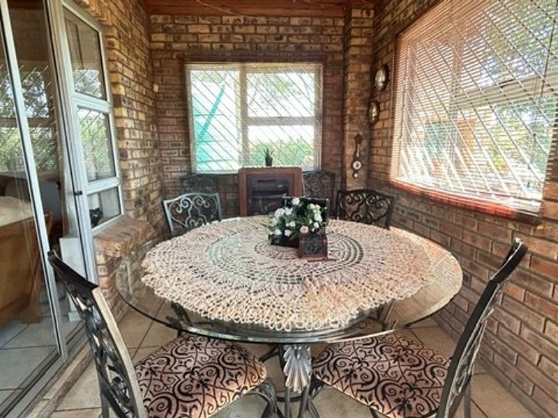 Enclosed patio area featuring exposed brick walls, tiled flooring, and large windows with security bars, providing a cozy transition space to the outdoors.
