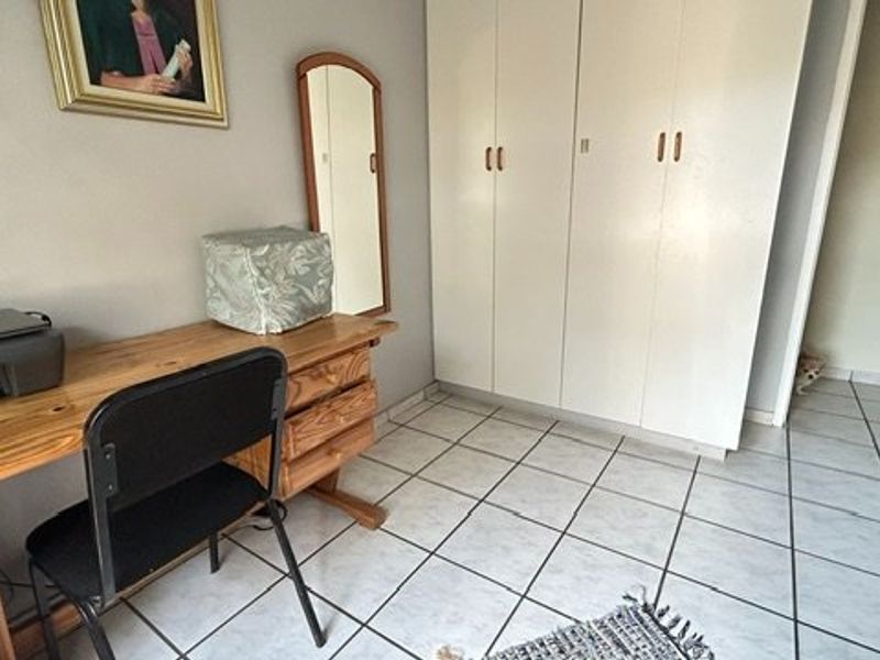 A bedroom featuring tiled flooring and built-in cupboards, currently utilized as a home office space.