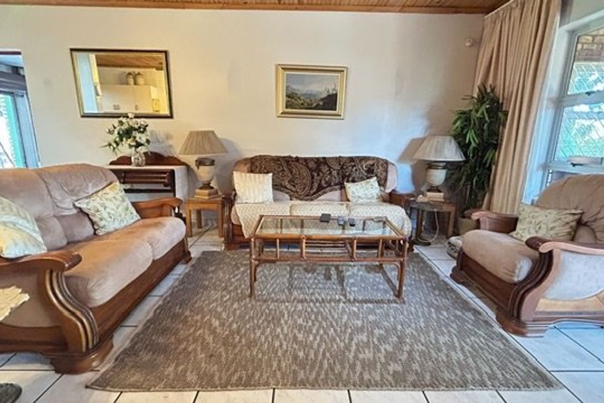 A comfortable living room featuring tiled flooring, a timber-paneled ceiling, and a large sliding glass door providing natural light.