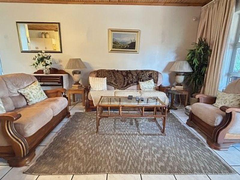 A comfortable living room featuring tiled flooring, a timber-paneled ceiling, and a large sliding glass door providing natural light.