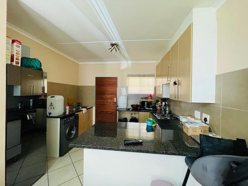 Functional kitchen featuring granite countertops, ample built-in cabinetry, a hob with extractor fan, and tiled flooring.
