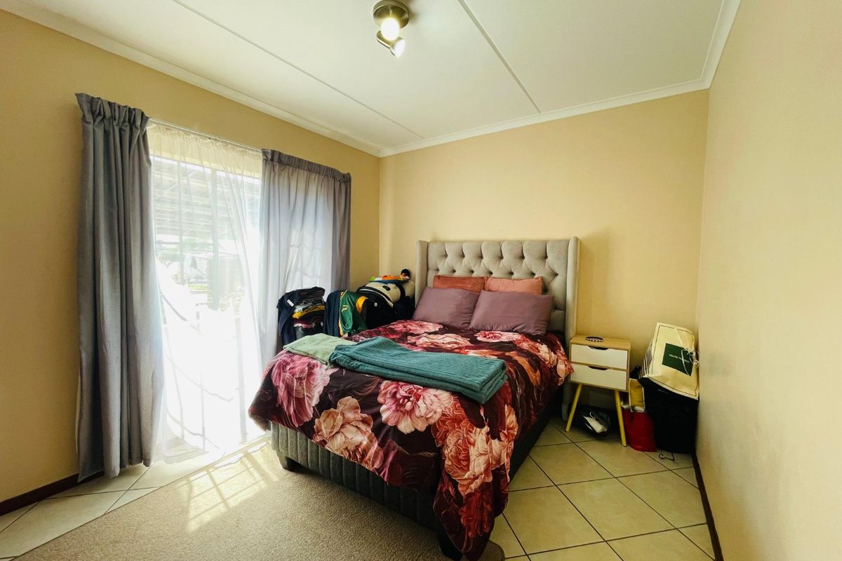 A bedroom featuring tiled flooring and a sliding glass door providing natural light.