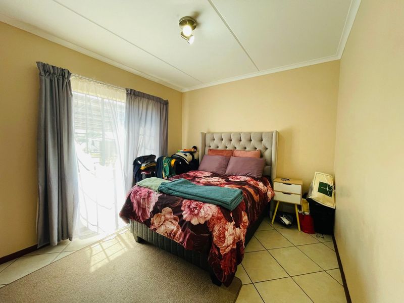 A bedroom featuring tiled flooring and a sliding glass door providing natural light.