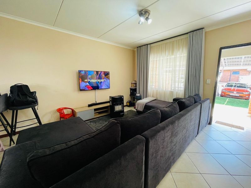 A functional living room featuring tiled flooring, neutral wall tones, and direct access to the exterior, providing a comfortable and practical living space.
