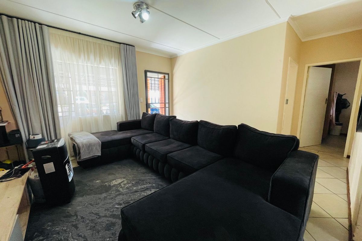 A living room featuring tiled flooring, a security gate at the entrance, and neutral wall finishes with ceiling-mounted lighting.