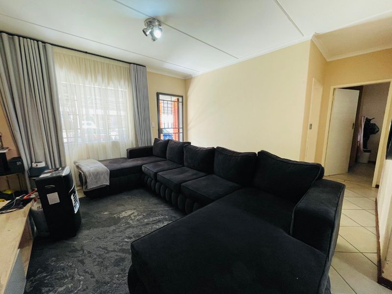 A living room featuring tiled flooring, a security gate at the entrance, and neutral wall finishes with ceiling-mounted lighting.