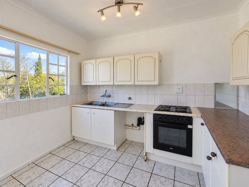 A functional kitchen featuring built-in cabinetry, laminate countertops, a double basin sink, and an integrated electric oven and hob with tiled flooring.