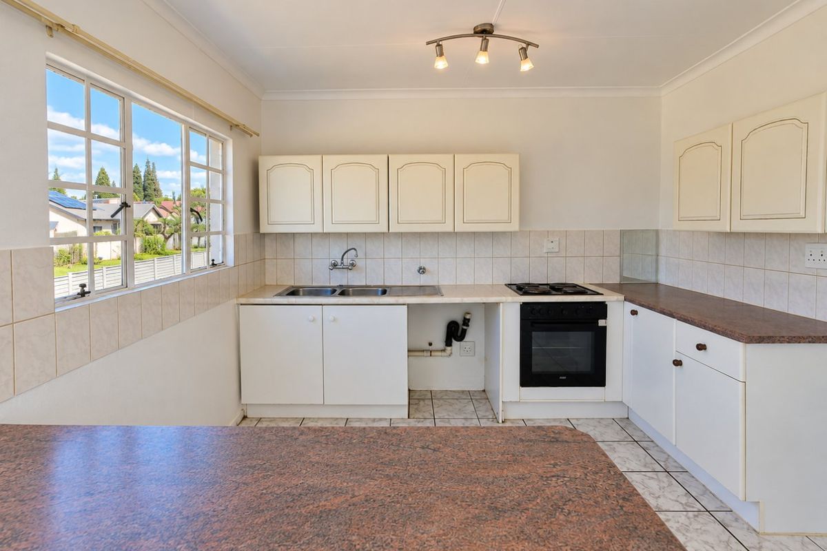 A functional kitchen featuring built-in cabinetry, laminate countertops, a gas hob, and an integrated oven, with tiled flooring and backsplash throughout.