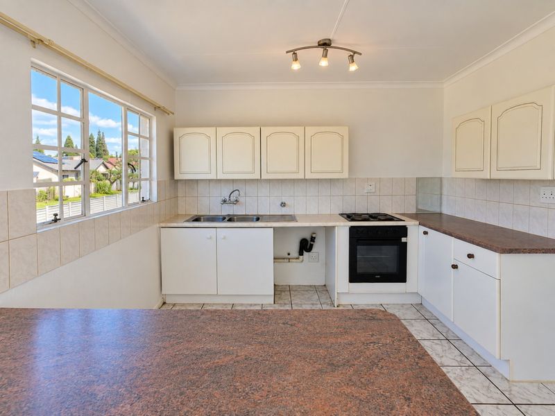 A functional kitchen featuring built-in cabinetry, laminate countertops, a gas hob, and an integrated oven, with tiled flooring and backsplash throughout.