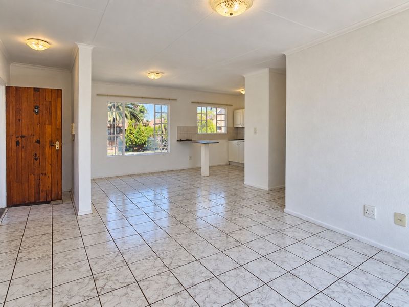 Spacious open-plan living and kitchen area featuring neutral tiled flooring, ample natural light, and a functional layout ready for personalization.