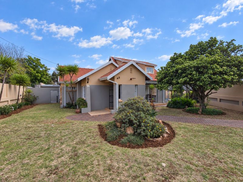 A well-maintained single-story residential property featuring a tiled roof, paved driveway, and established garden with boundary walling.