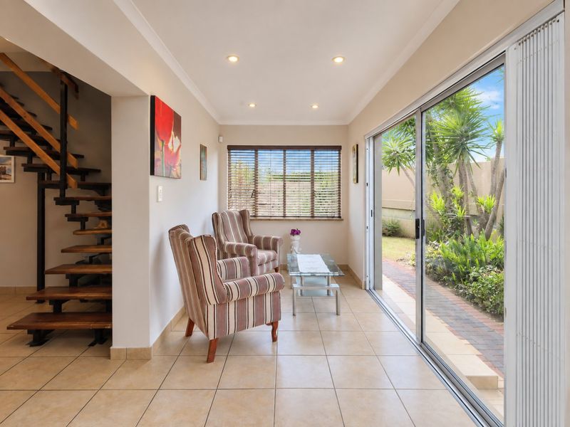 Bright living area featuring tiled floors, an open-tread staircase, and large sliding glass doors providing direct access to the garden.