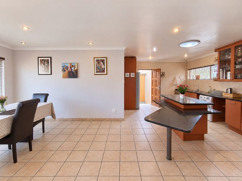 Open-plan kitchen and dining area featuring tiled flooring, granite countertops, a kitchen island, and ample cabinetry with integrated lighting.