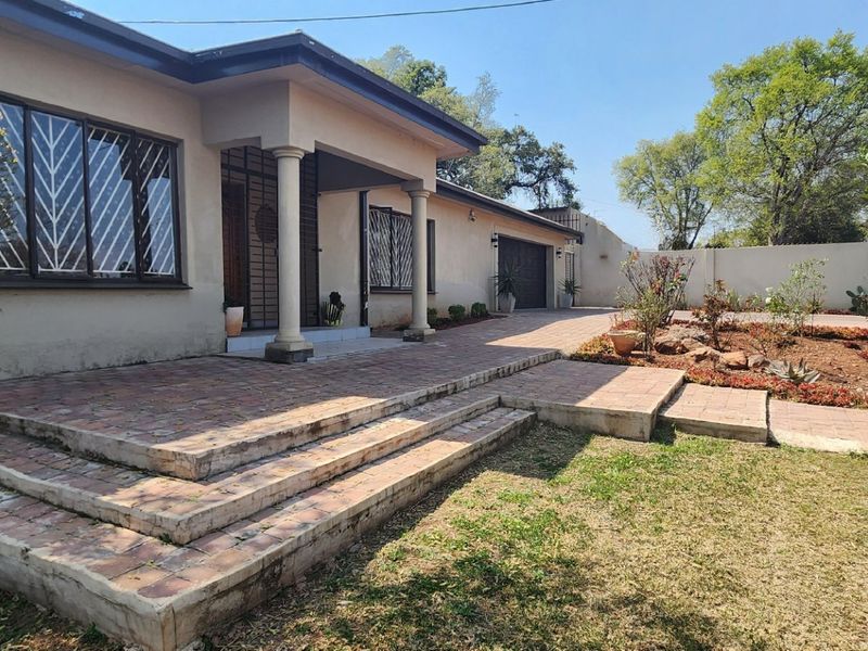 Front elevation of a single-story house featuring a covered entrance with concrete columns, brick paved patio, and an attached garage.