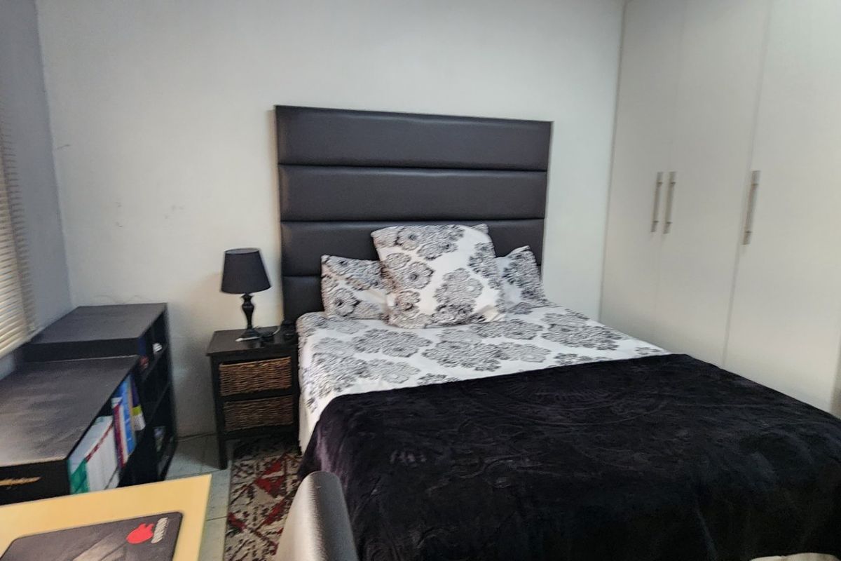 A functional bedroom featuring a built-in wardrobe and venetian blinds, providing essential storage and light control.
