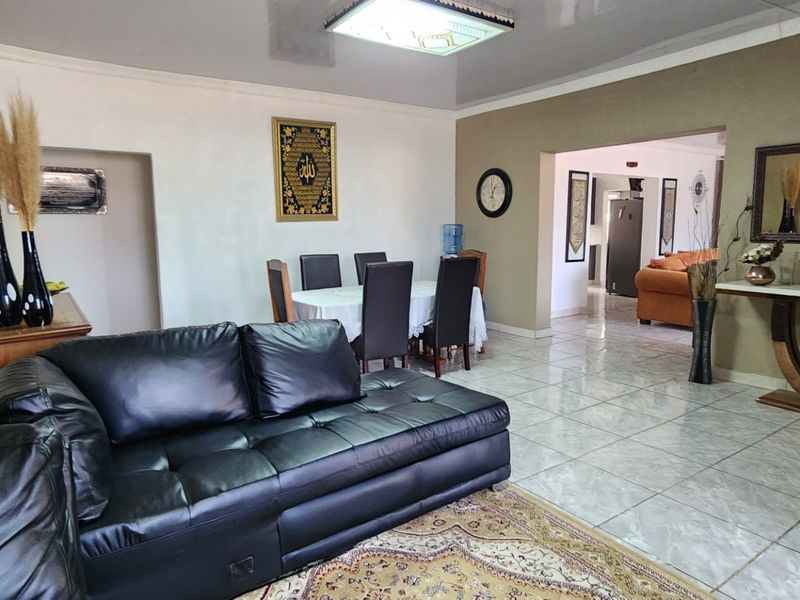 Spacious open-plan living and dining area featuring neutral wall tones, glossy tiled flooring, and a modern recessed ceiling design.