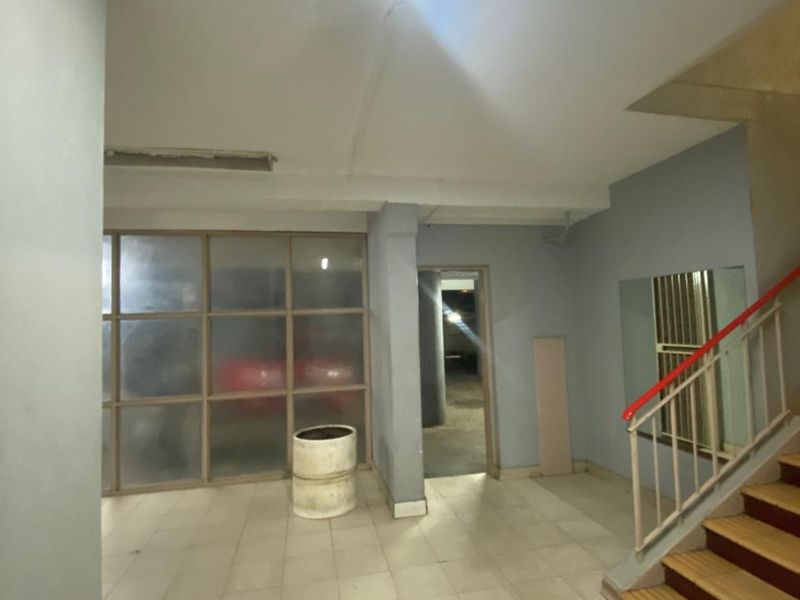 A functional apartment building hallway featuring tiled flooring, a staircase with a metal railing, and a glass partition wall.