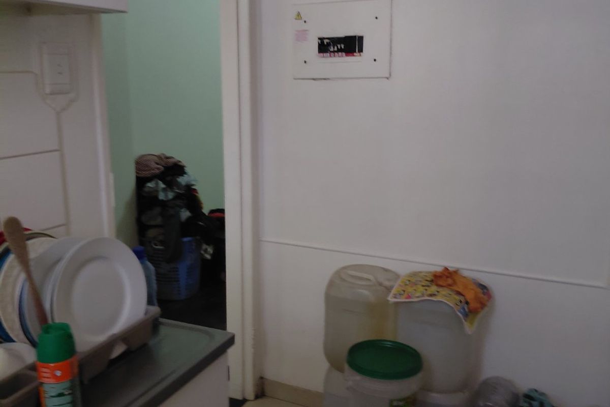 A functional kitchen area featuring built-in cabinetry, tiled flooring, and exposed ventilation ducting, providing a practical layout for daily use.