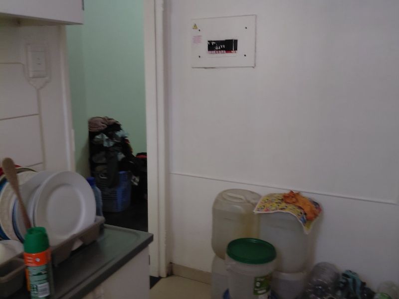 A functional kitchen area featuring built-in cabinetry, tiled flooring, and exposed ventilation ducting, providing a practical layout for daily use.