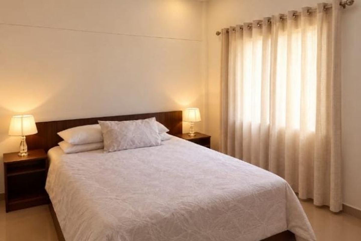 A well-maintained bedroom featuring a built-in headboard, neutral wall finishes, and window treatments with a curtain rod.