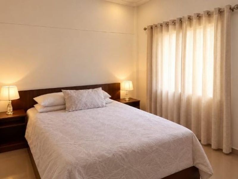 A well-maintained bedroom featuring a built-in headboard, neutral wall finishes, and window treatments with a curtain rod.