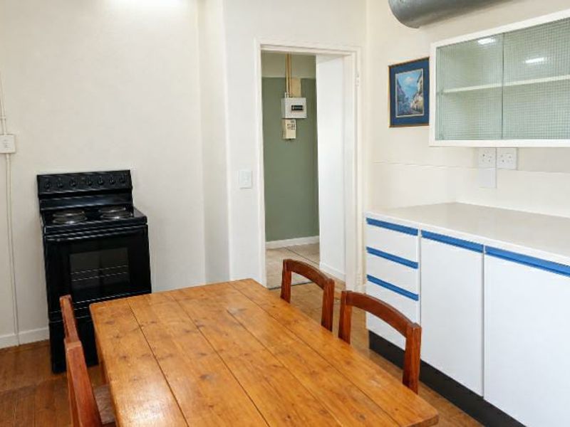 A functional kitchen area featuring built-in cabinetry, a glass-fronted wall unit, and a freestanding electric stove, with an adjacent utility space visible.