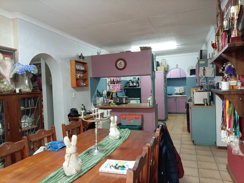 Open plan dining and kitchen area featuring dated cabinetry, tiled flooring, and a traditional archway connecting the living space.