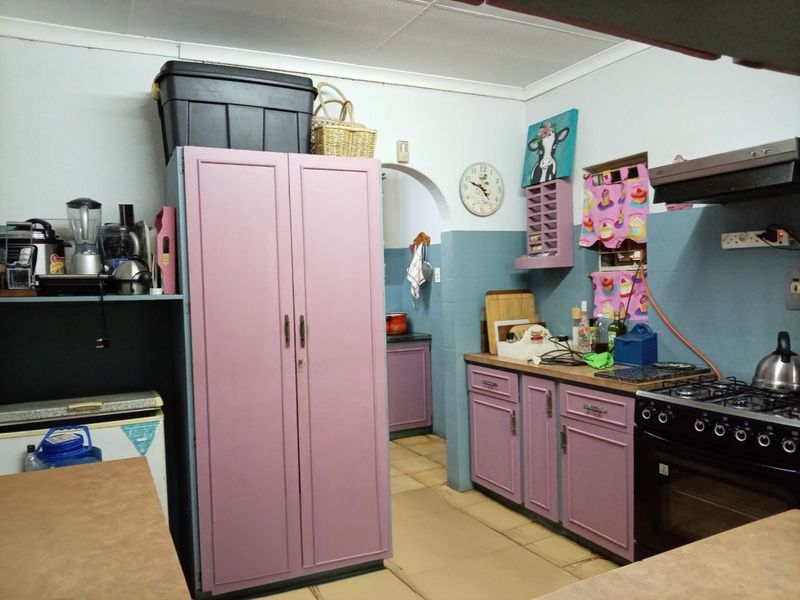 A functional kitchen featuring built-in cabinetry, a gas stove with extractor fan, and an arched doorway leading to an adjacent utility area.