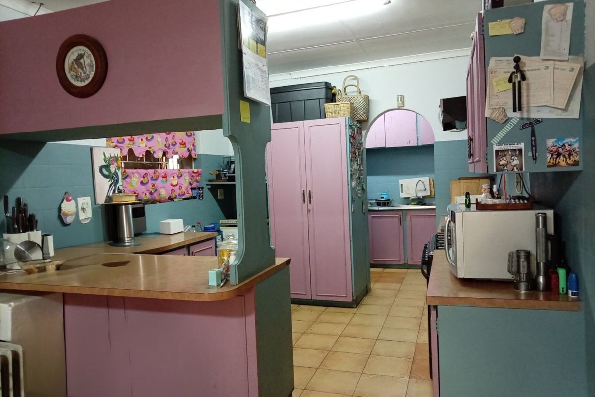 A dated kitchen featuring built-in cabinetry, laminate countertops, and ceramic tile flooring, offering significant potential for modernization and renovation.