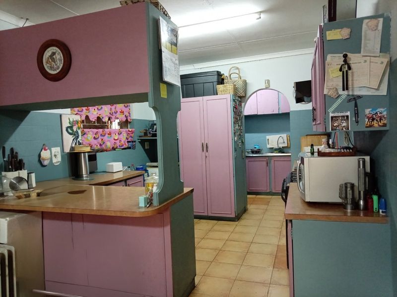 A dated kitchen featuring built-in cabinetry, laminate countertops, and ceramic tile flooring, offering significant potential for modernization and renovation.