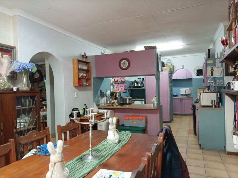 Open plan kitchen and dining area featuring dated cabinetry, a breakfast counter, and an arched entryway connecting to adjacent living spaces.