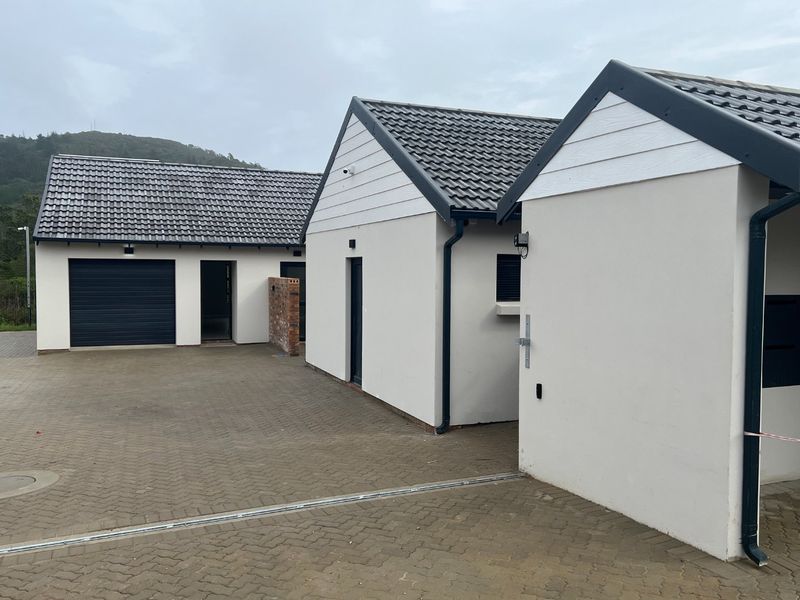 Modern residential exterior featuring a paved driveway, multiple garage access points, and clean, contemporary architectural finishes.