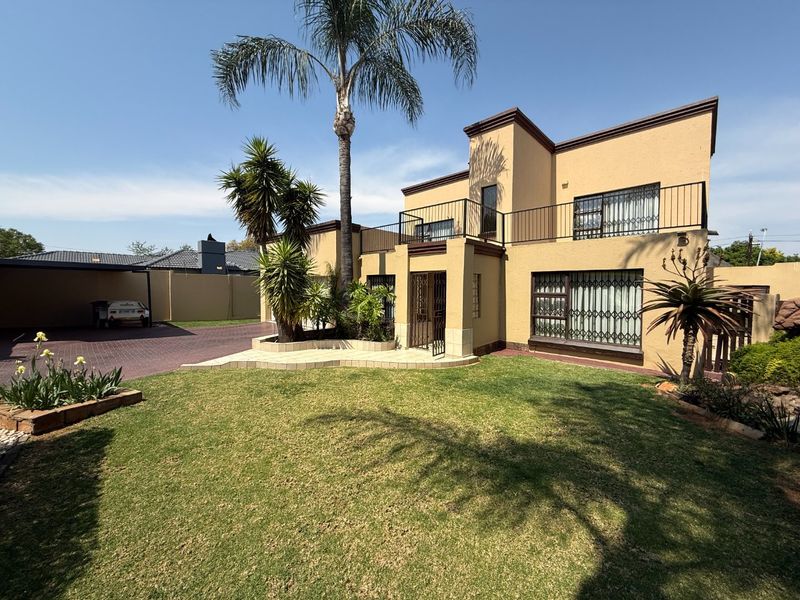 A well-maintained double-story residential property featuring a paved driveway, a front garden, and a balcony with metal railings.