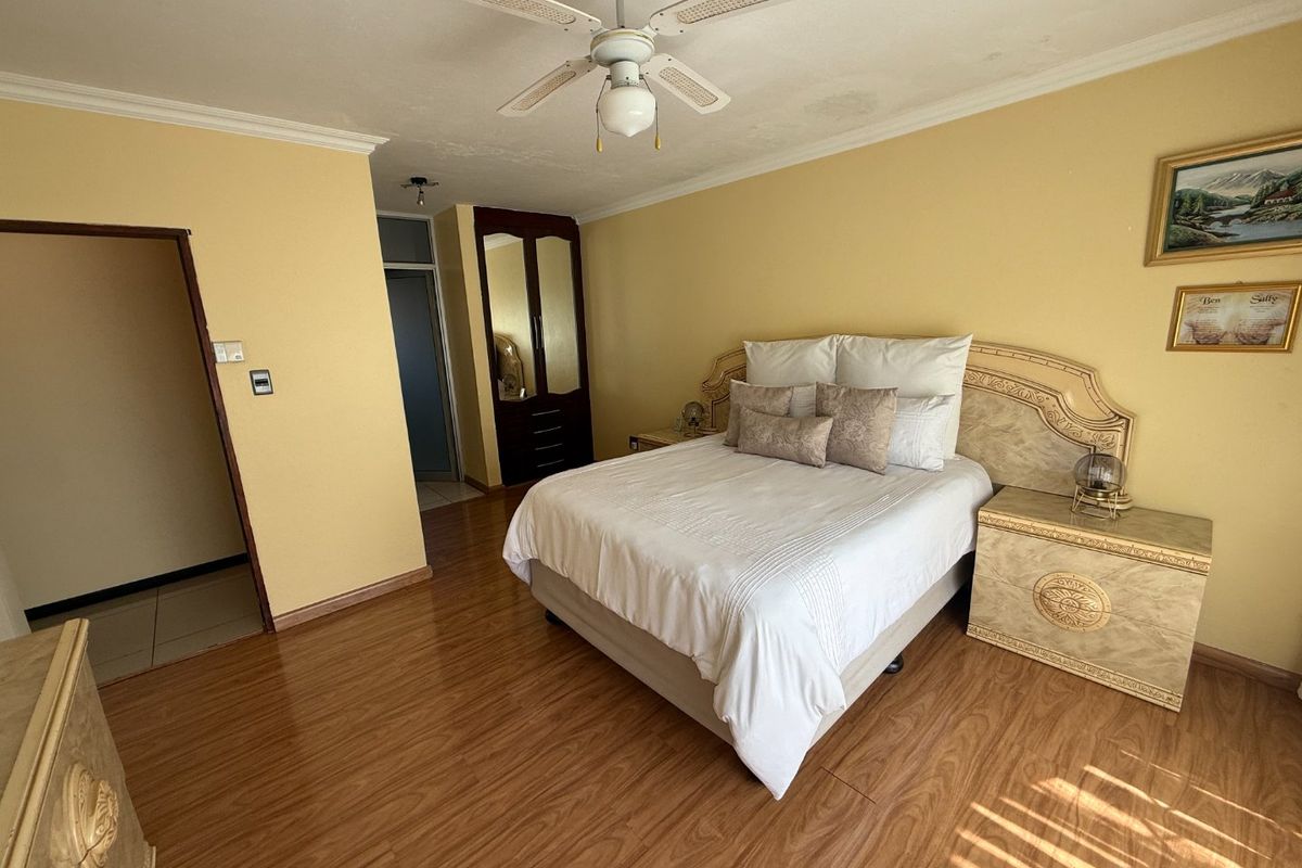 Spacious bedroom featuring laminate flooring, a ceiling fan, and built-in wardrobe storage.