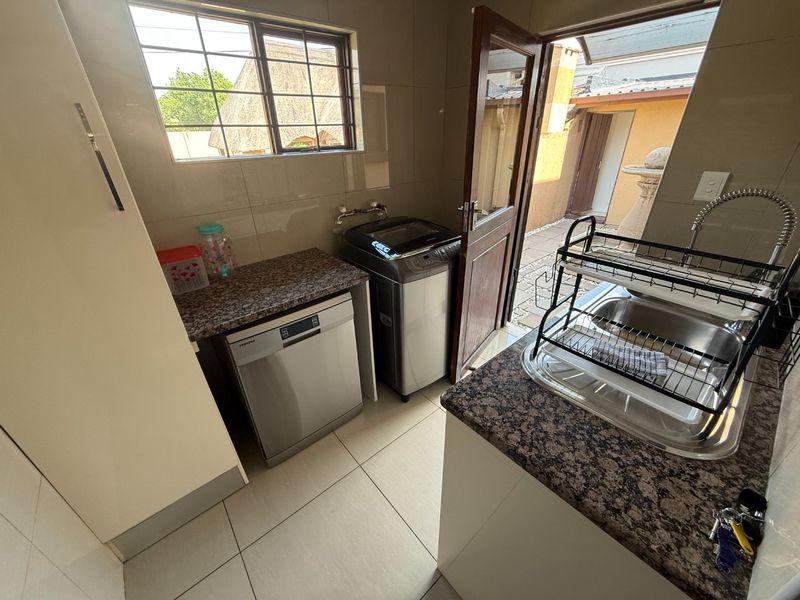 A functional laundry area featuring granite countertops, tiled finishes, and direct access to the exterior.