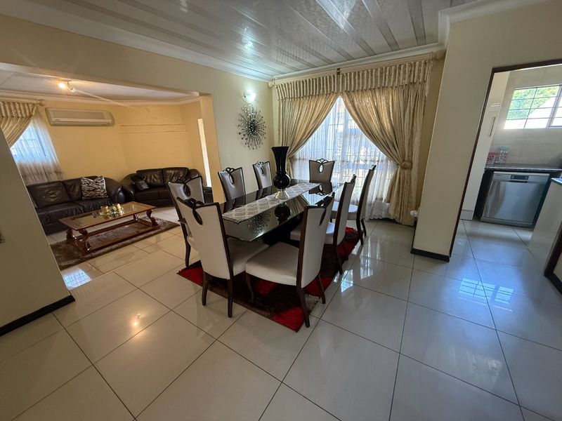 Open-plan living and dining area featuring polished floor tiles, coved ceilings, and an integrated kitchen space with modern appliances.
