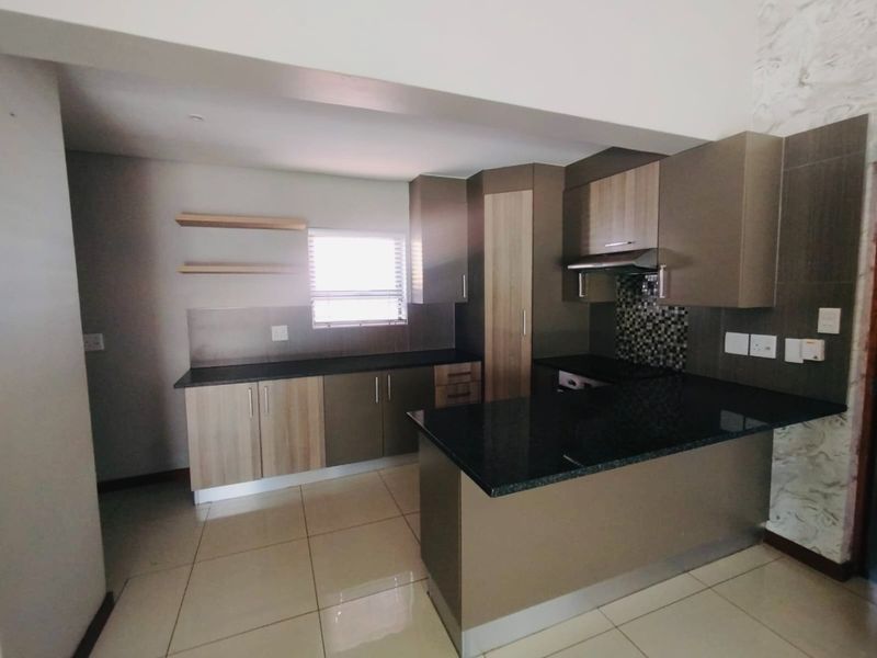 Modern kitchen featuring sleek built-in cabinetry, granite countertops, a mosaic tile backsplash, and an integrated extractor fan, offering a clean and functional workspace.
