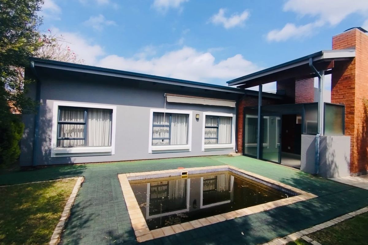 Rear exterior view featuring a paved patio area and a swimming pool with a brick chimney structure attached to the main dwelling.